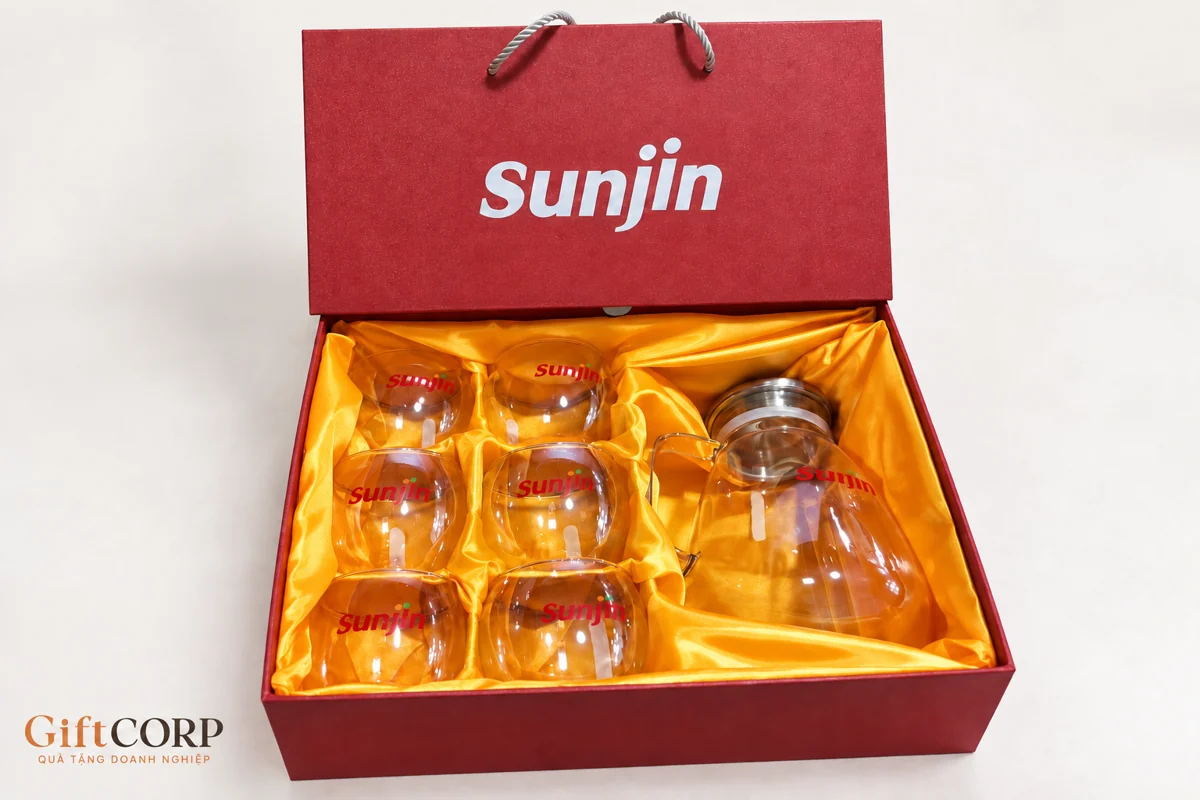 Hộp đỏ lót vàng với sáu ly và bình có nhận diện Sunjin trên nền sạch