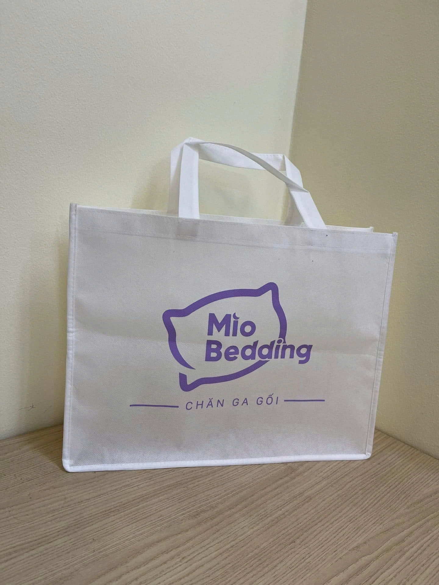 Túi trắng hai quai có nhận diện Mio Bedding màu tím ở một mặt