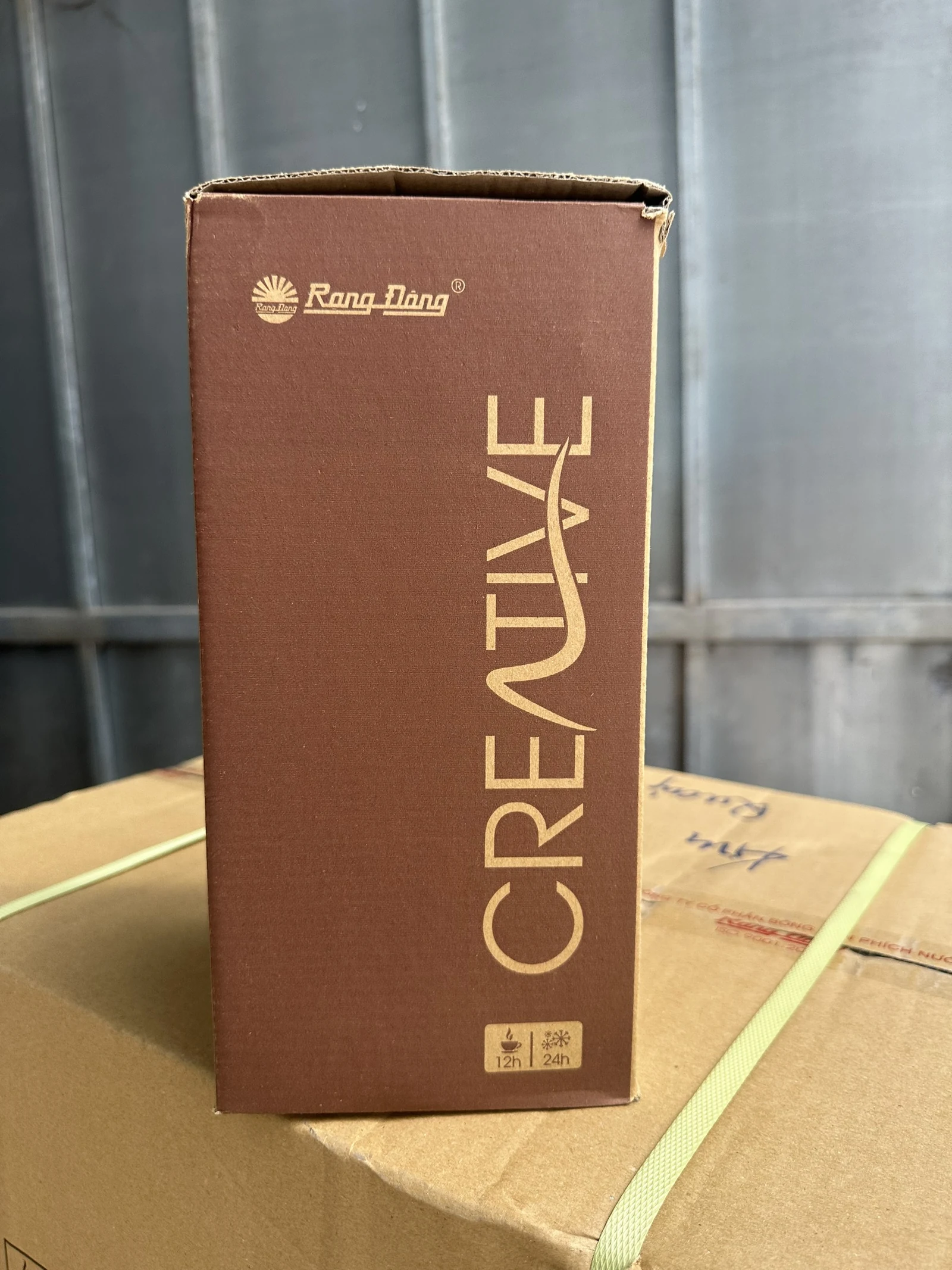 Hộp nâu Rạng Đông đang mở miệng trên kiện carton có dây đai