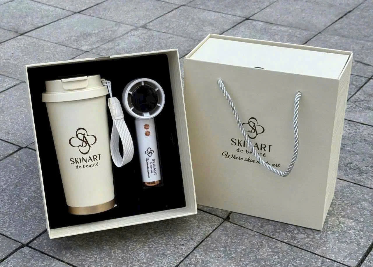 Ảnh hộp có ly màu kem cùng thiết bị cầm tay và bao bì có quai in SKINART