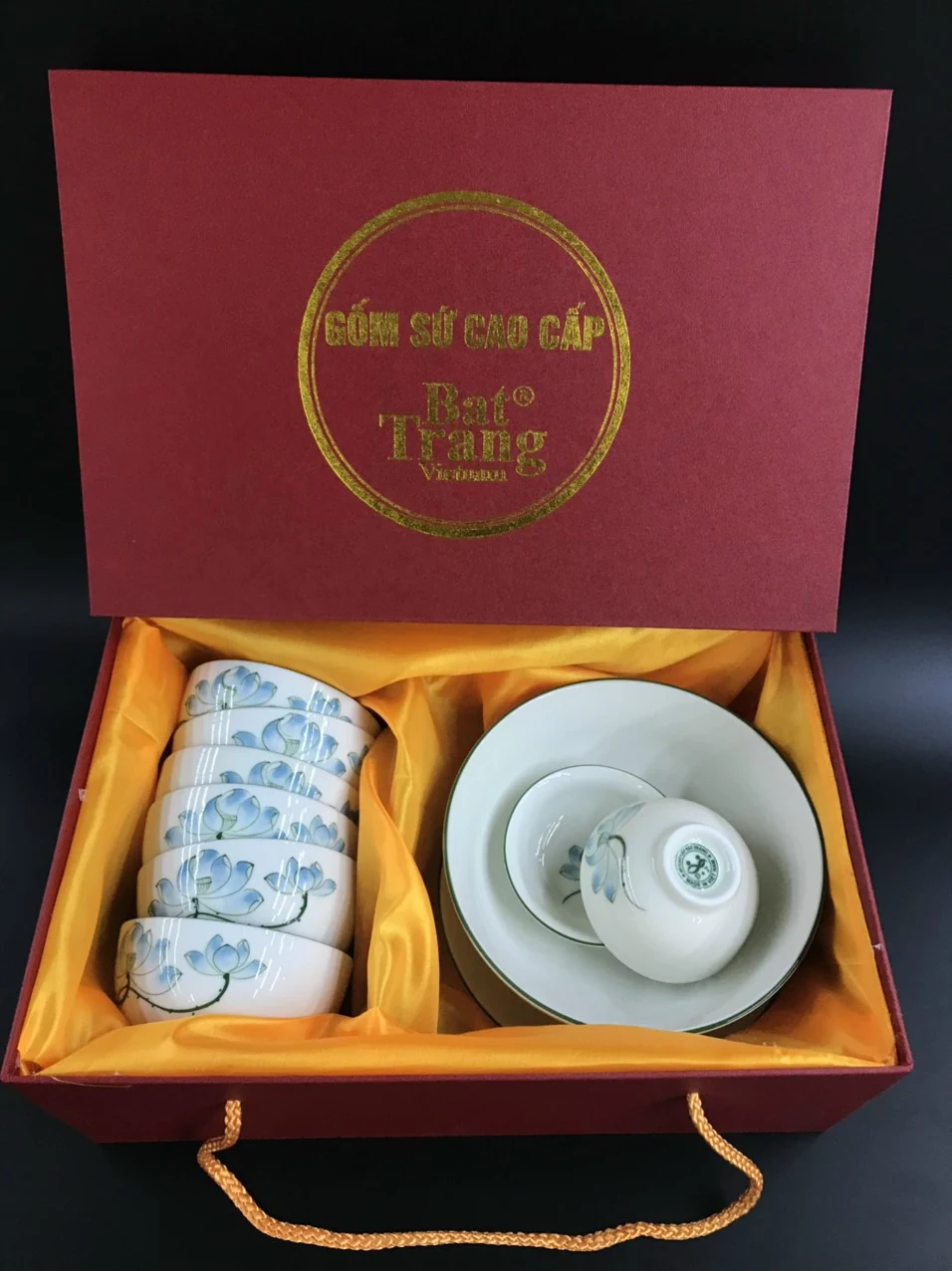 Ảnh hộp đỏ mở lót vàng, một vùng bát xếp chồng và một vùng đĩa cùng bát nhỏ