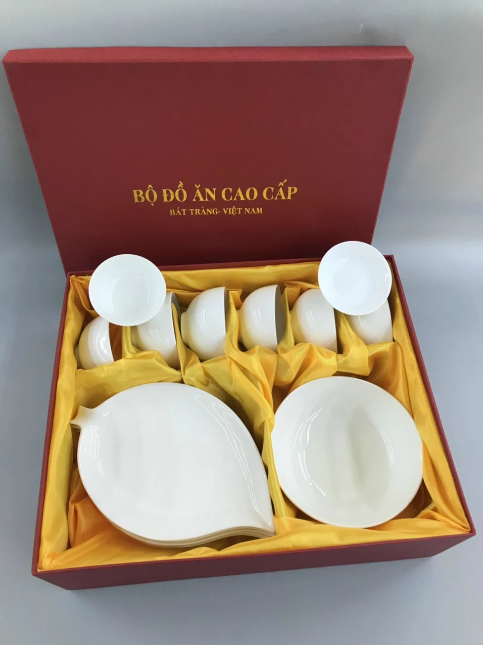 Ảnh hộp đỏ lót vàng với các bát và đĩa trắng ở nhiều vùng chia ngăn