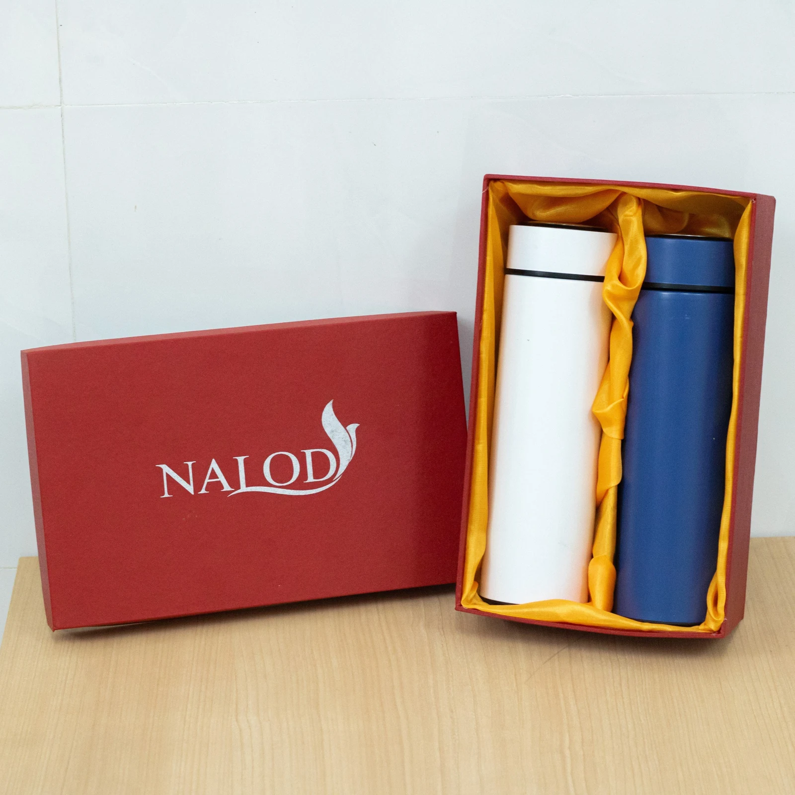 Hai bình trắng và xanh đứng trong hộp đỏ lót vàng, nắp hộp đặt bên trái