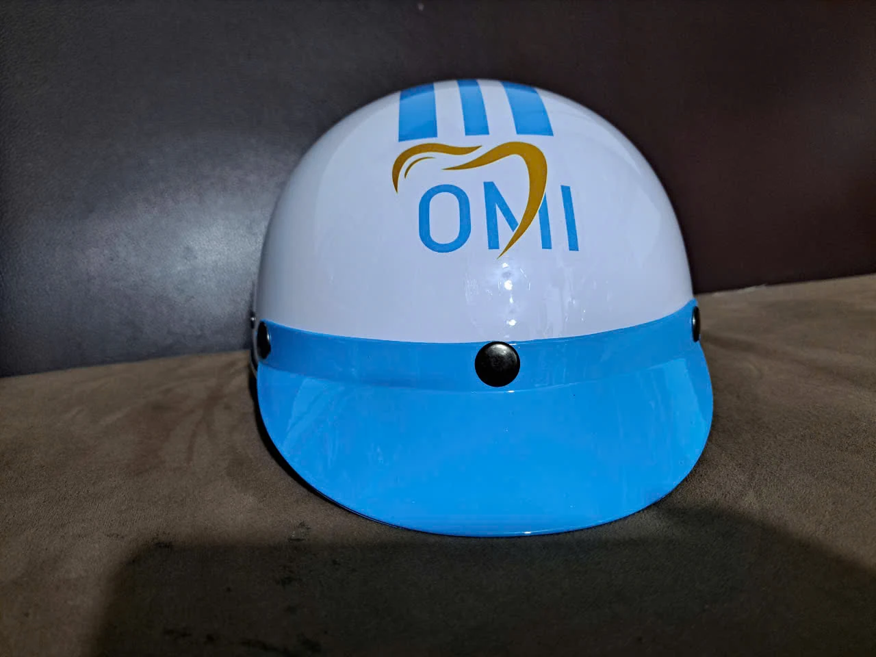 Mũ trắng và vành xanh chụp từ trước, logo OMI trên thân