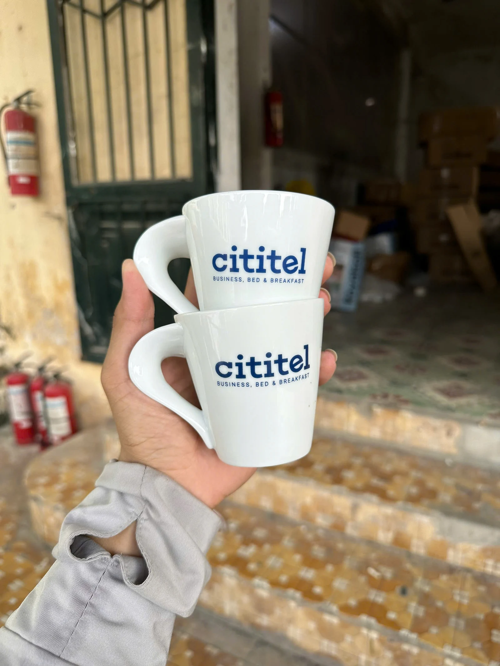 Hai cốc trắng có logo và dòng chữ nhỏ màu xanh