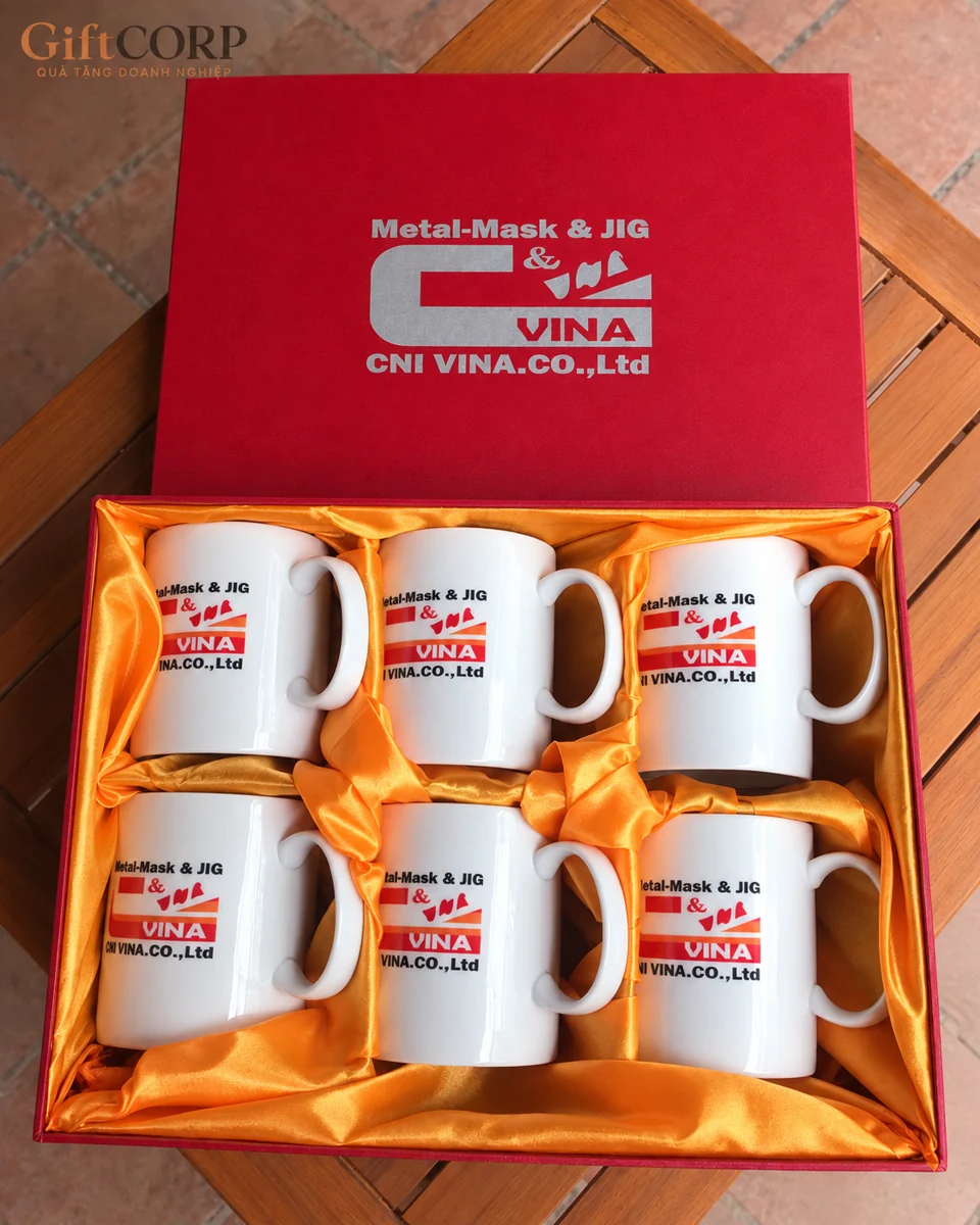 Sáu cốc trắng trong hộp lót vàng, nắp đỏ và nhận diện CNI VINA ở các nền khác nhau